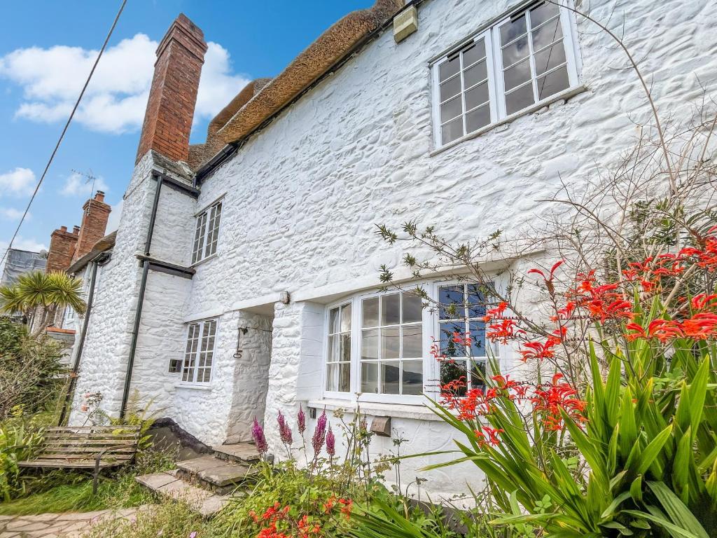 a white house with red flowers in front of it at The Crows Nest Porlock Weir in Porlock