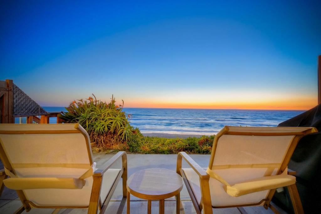 two chairs and a table with a view of the ocean at Oceanfront Condo, Private Patio, Beach Access, Sunset Views in Carlsbad