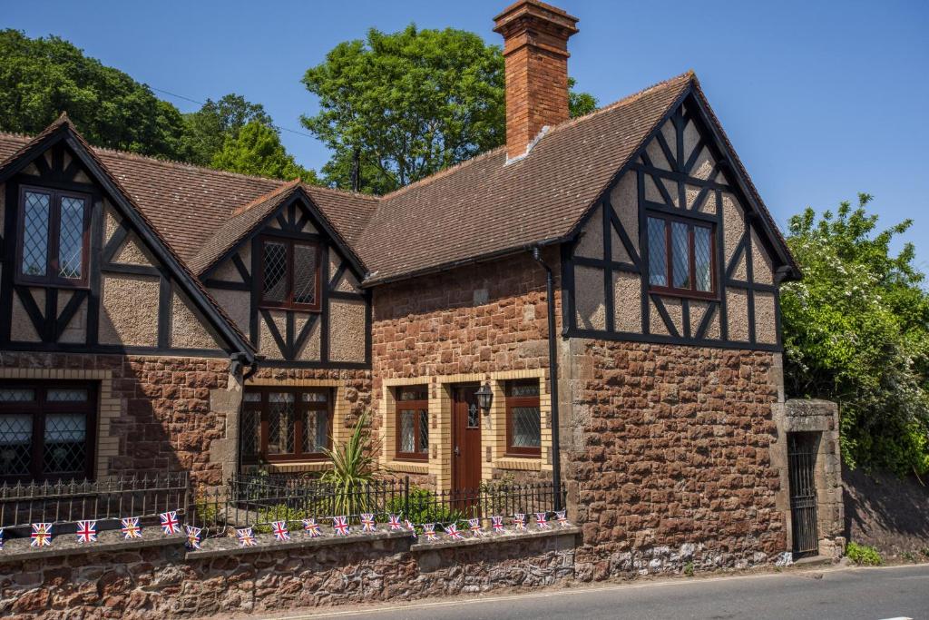 a brick house with a chimney on a street at Two Grooms Cottage Dunster in Dunster