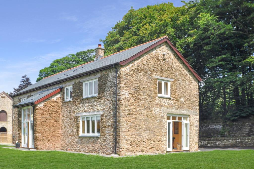 an old brick house on a grass field at The Wool Barn Simonsbath in Exford