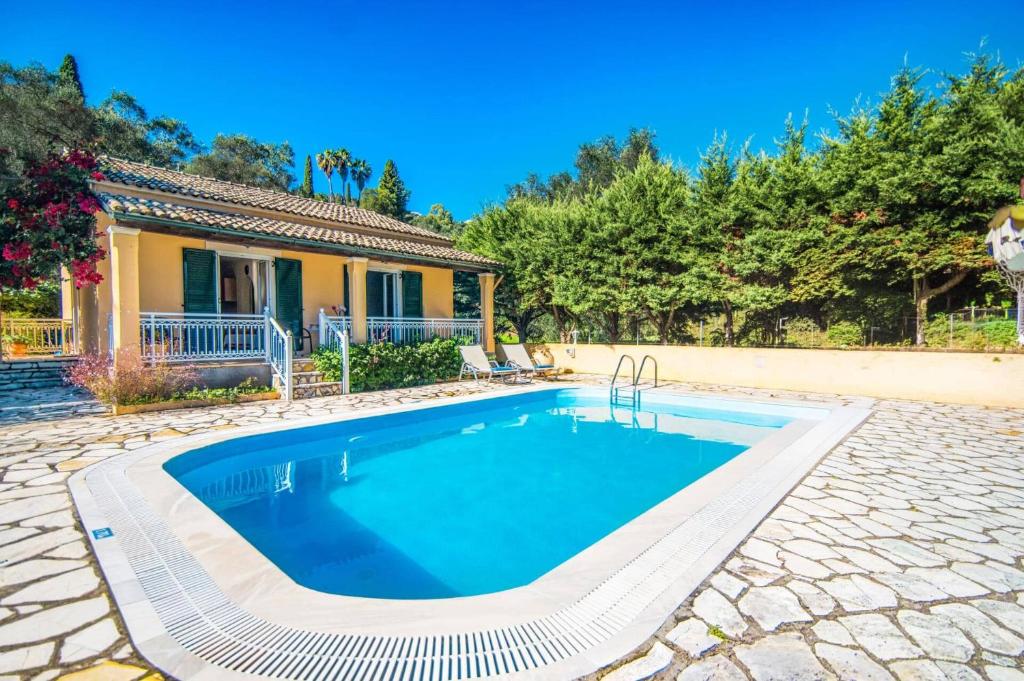 a swimming pool in front of a house at Villa Marias Beach House by Villa Plus in Ágios Stéfanos