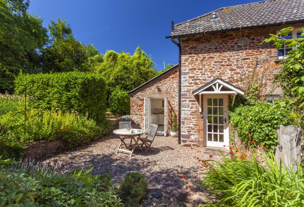 a stone cottage with a table and chairs in front of it at Horner Cottage Luccombe in Minehead