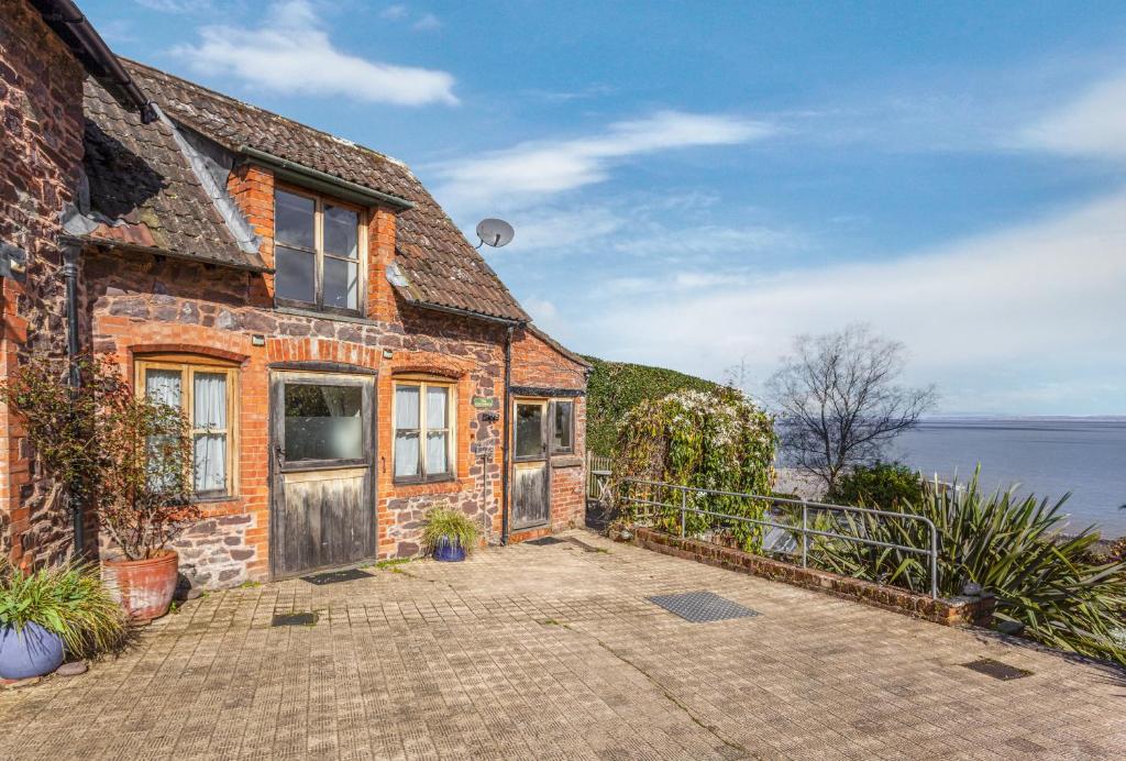 an old brick house with a view of the ocean at The Coach House Porlock Weir in Porlock