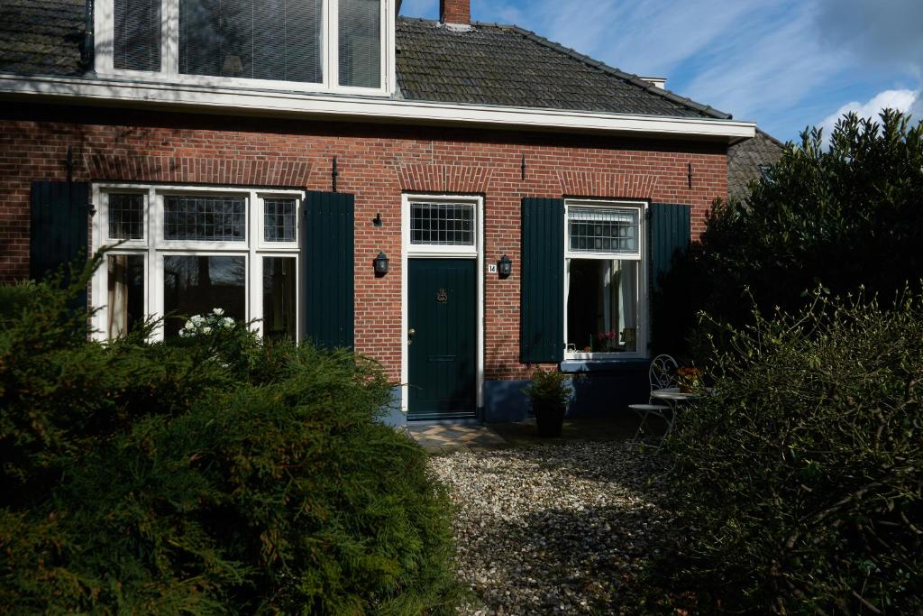 a red brick house with a green door at B&B Chez Nous in Geesteren
