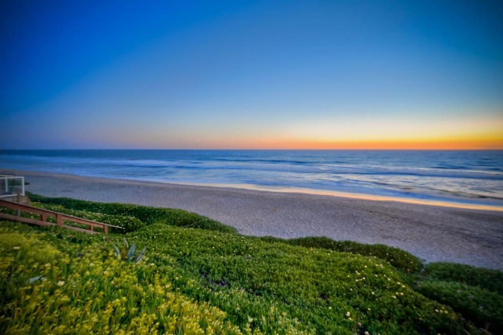 a view of a beach with the sunset in the background at Oceanfront Apartment, Private Balcony, Beach Access, Sunset Views in Carlsbad