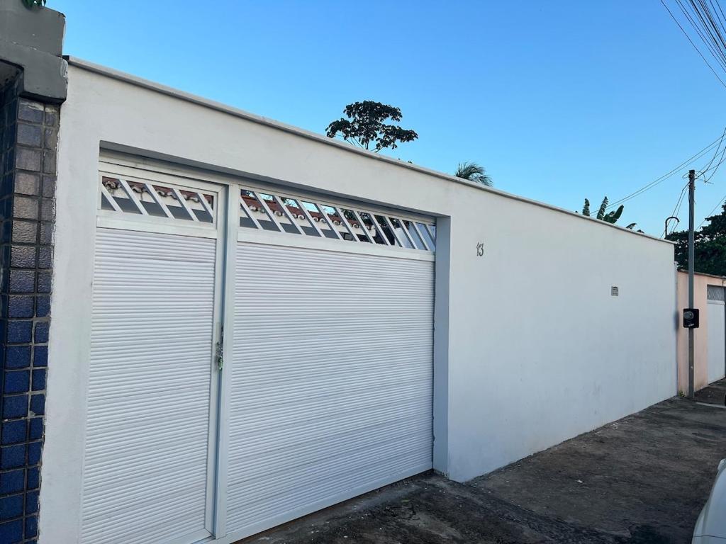 a white garage door on a white building at Casa com ampla área externa de lazer in São Luís