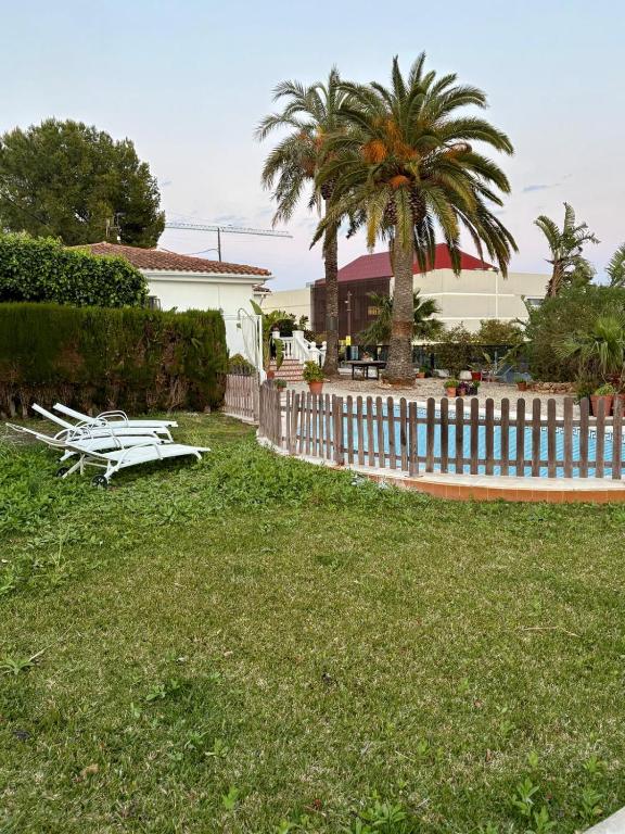 a yard with a white fence and a palm tree at Chalet Eucaliptus in Alcossebre