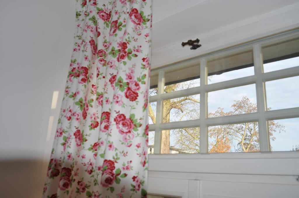 Una ventana con una cortina con rosas. en Appartement Hundackerweg en Essen