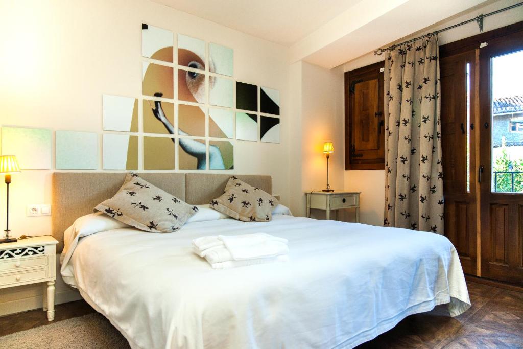 a bedroom with a white bed with a picture on the wall at Abadía San Martín in San Martín del Castañar