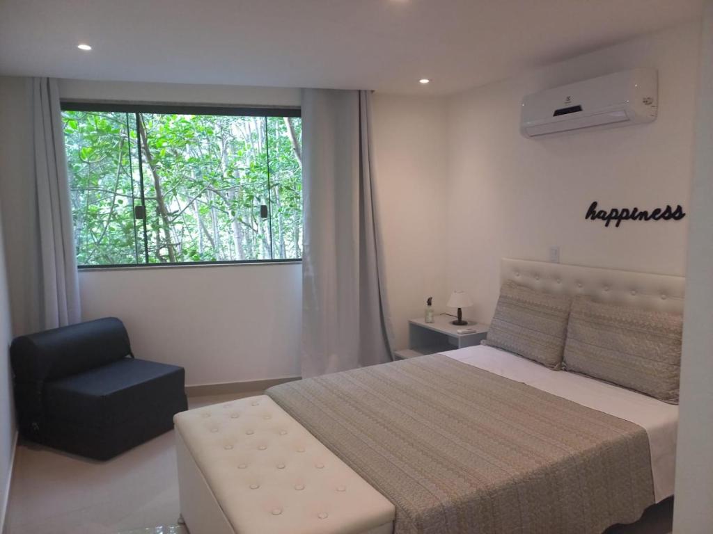 a bedroom with a bed and a chair and a window at Casa ampla in Maricá
