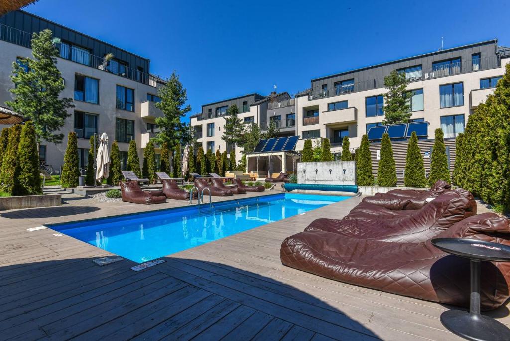 a swimming pool with brown reclining chairs and buildings at Vidmantės apartamentai in Palanga