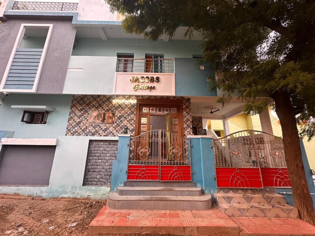 a house with a red front door and a tree at Jacobs Cottage KG-F2 in Thiruchendur