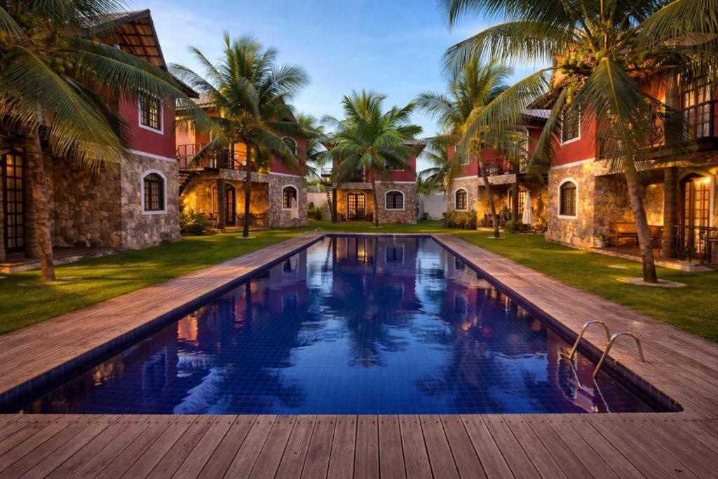 a swimming pool in front of a house with palm trees at Chalé De Canoa in Aracati