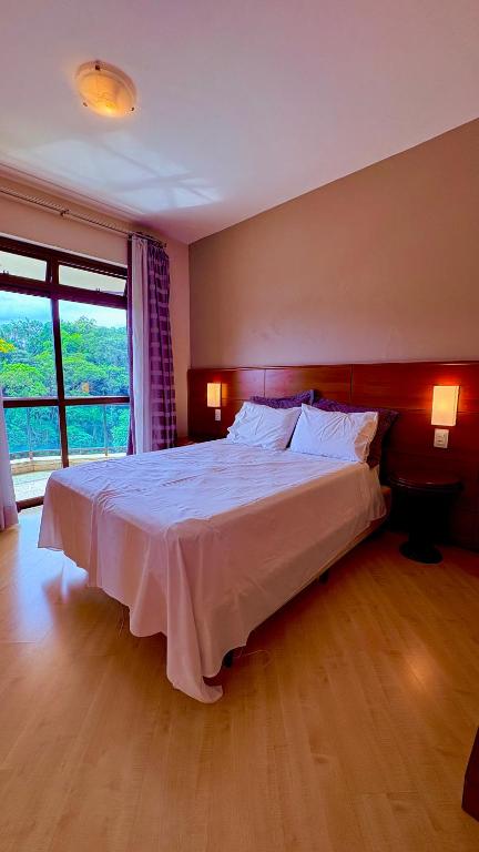 a bedroom with a large bed with a large window at Suite master, condo-hotel in Joinville