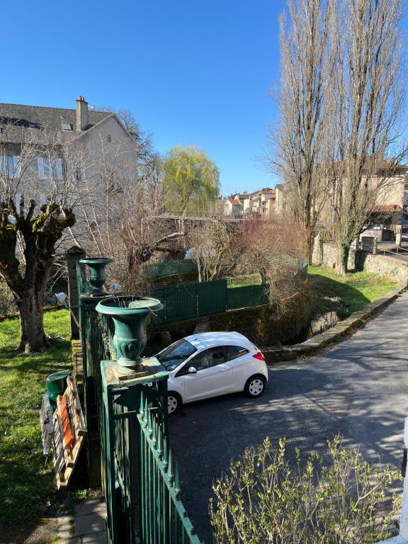 a white car parked next to a green fence at Le Rive & Chêne Apartment in Aurillac