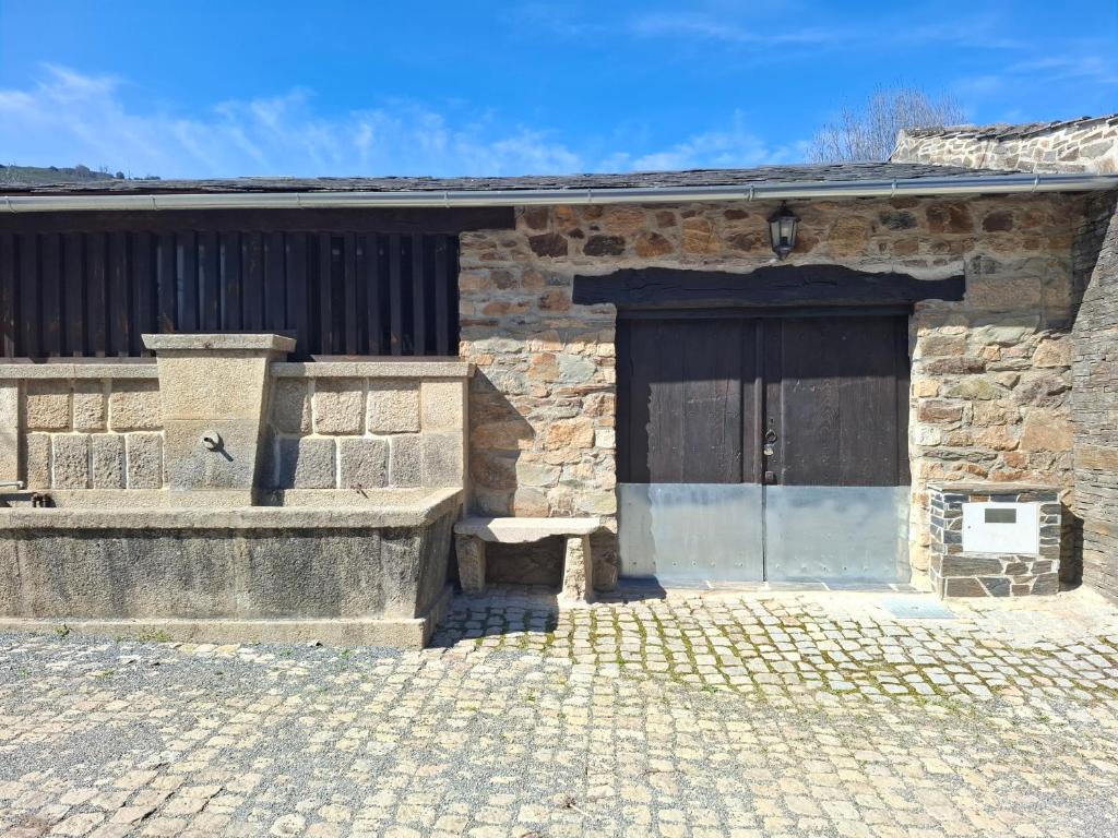 a stone building with a large door and a bench at Cantinho do Lello in Bragança