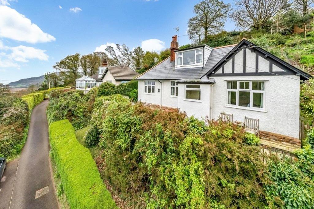 a white house on a hill with a road at West Wind Porlock in Porlock
