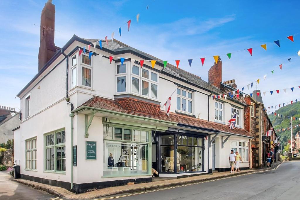 a white building with flags on a street at Keld Apartment Porlock in Porlock