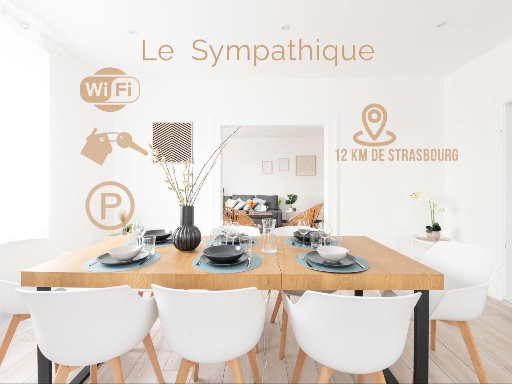 a dining room with a wooden table and white chairs at Le sympathique in Ittenheim