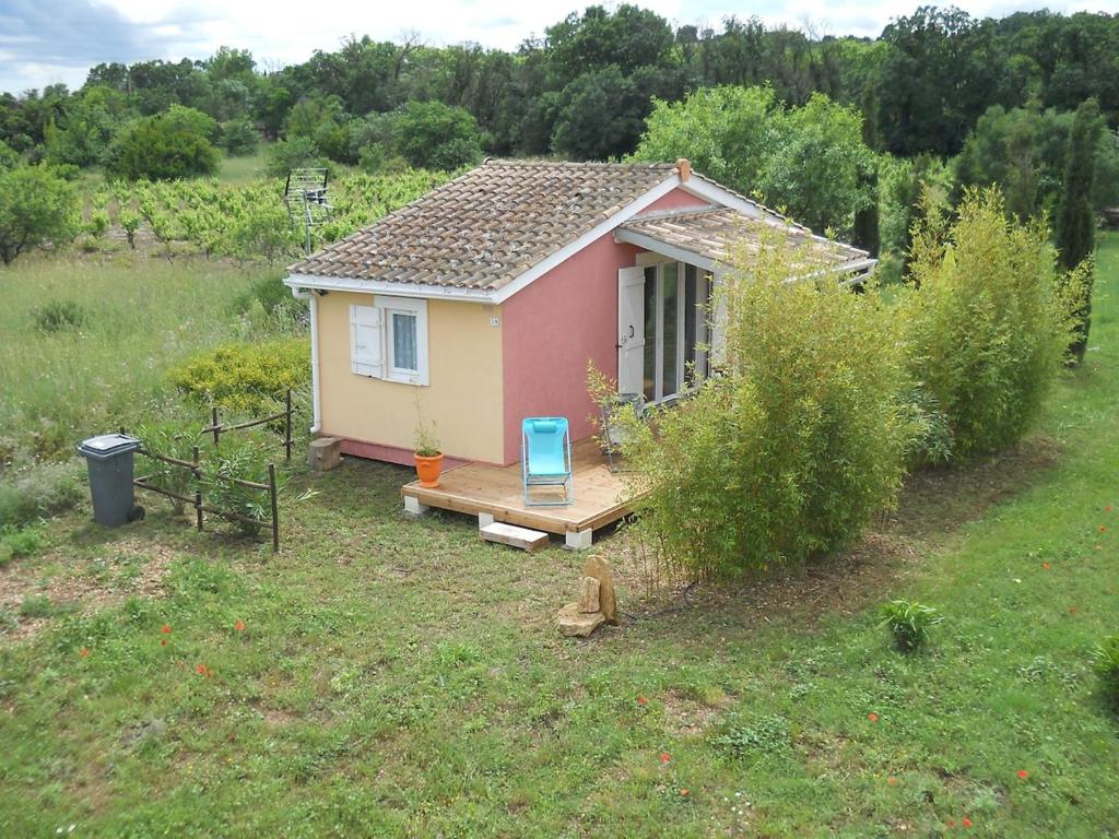 a small pink house with a wooden porch in a field at chalet nature 2 in Aspiran