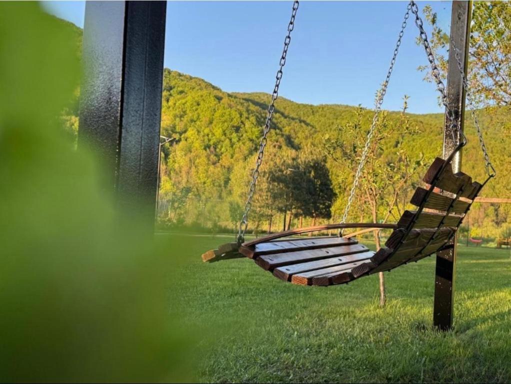 a wooden swing in a field with a mountain at Котедж в ГОРАХ in Solochyn