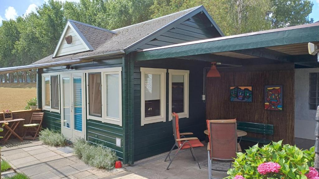 a green house with a table and chairs on a patio at Artistiek Vakantiehuisje in Hulst