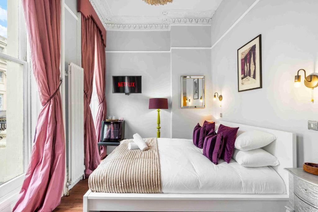 a bedroom with a white bed with purple pillows at Orien tal By My Getaways in Brighton & Hove