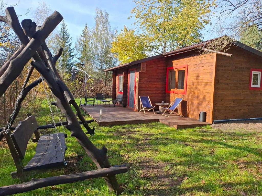 a log cabin with a deck and a bench at Domek w ogrodzie "Bzyczek" in Ostry Bór