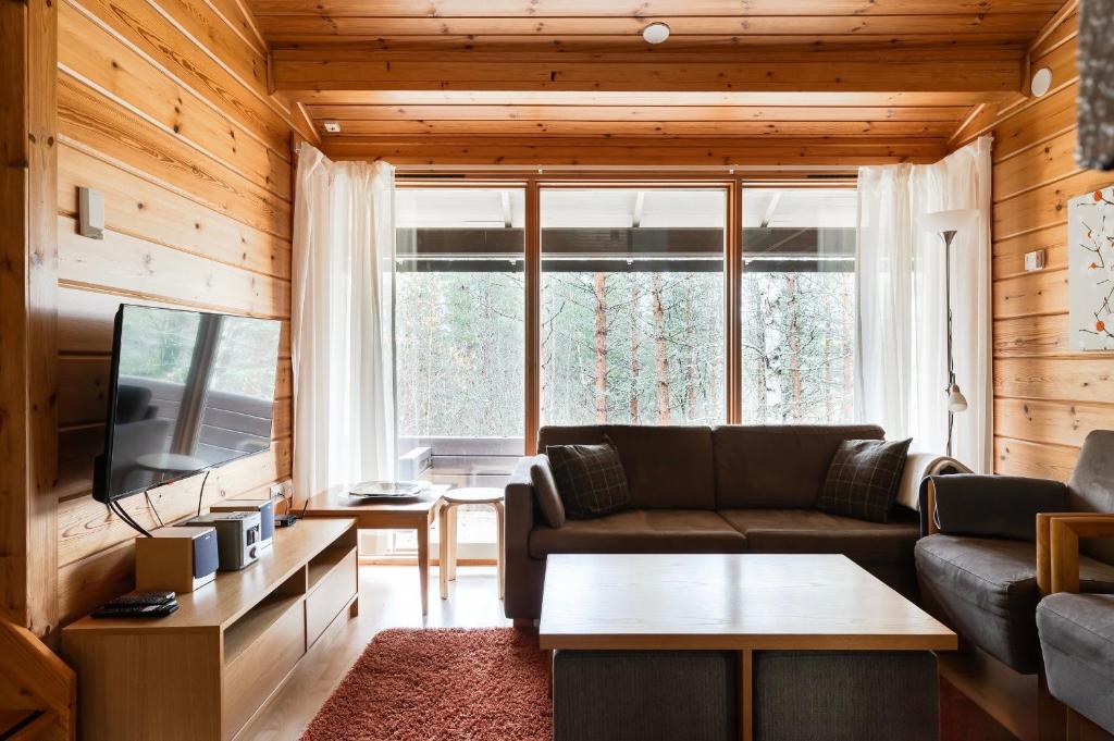 a living room with a couch and a tv at Mökki Vierumäki in Myllykylä