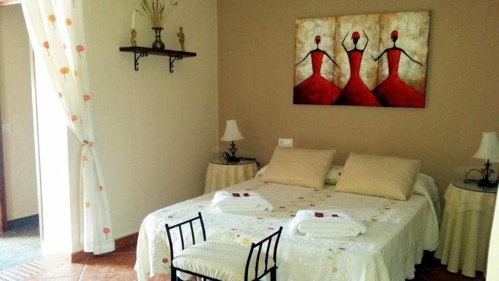 a bedroom with a bed with two chairs and a painting at Castor y Polux in El Gastor