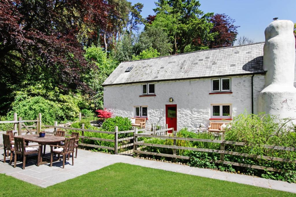 a white cottage with a table and chairs in front of it at Cascade Cottage Exford in Exford