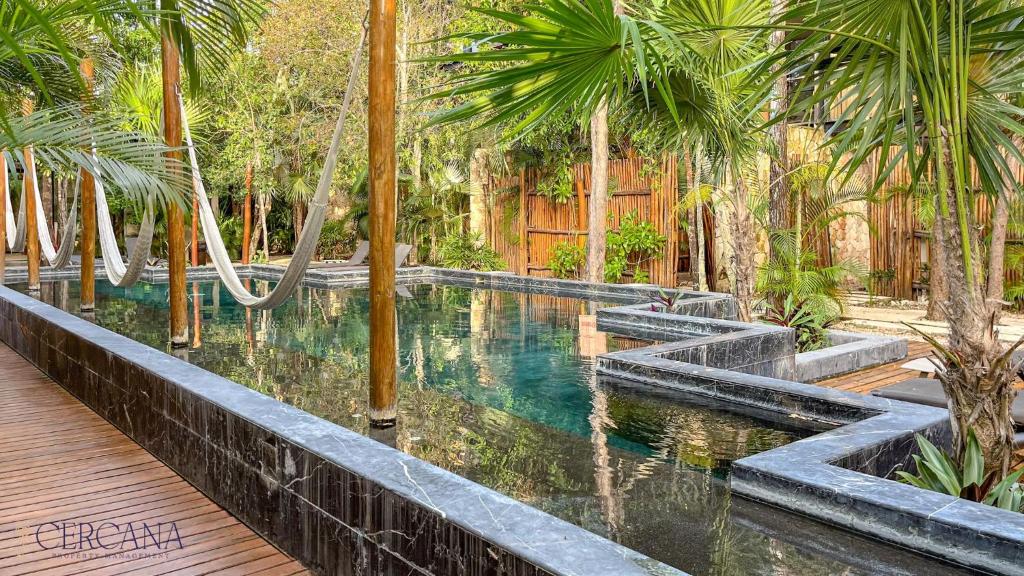 a swimming pool in a resort with palm trees at Amaka Calma Tulum by Cercana in Tulum