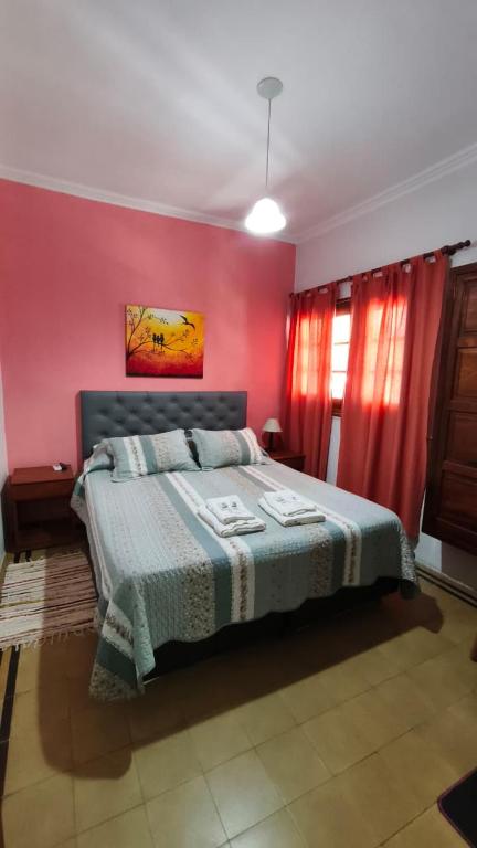 a bedroom with a bed in a pink wall at Hostería La Pergola in Villa Serranita
