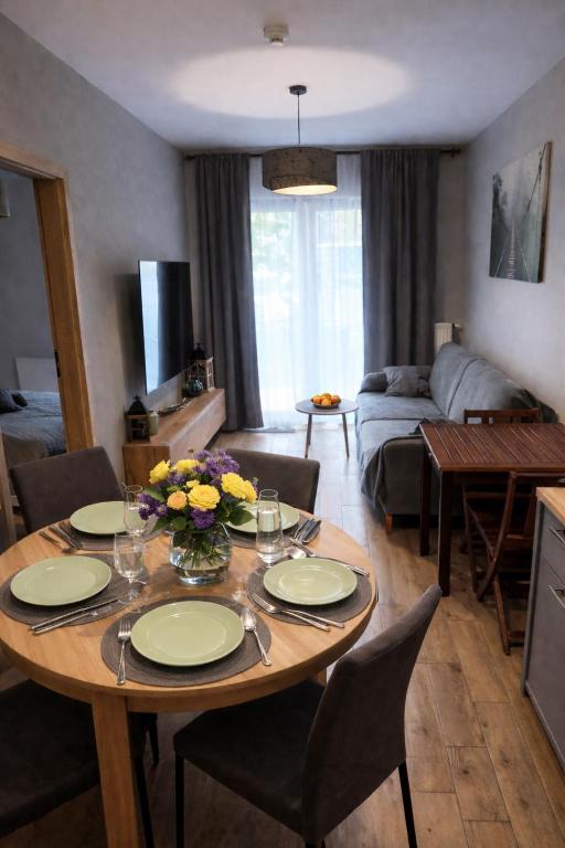 a living room with a table with plates and flowers on it at Apartament Słoneczna Dolina SPA Belle View in Szklarska Poręba