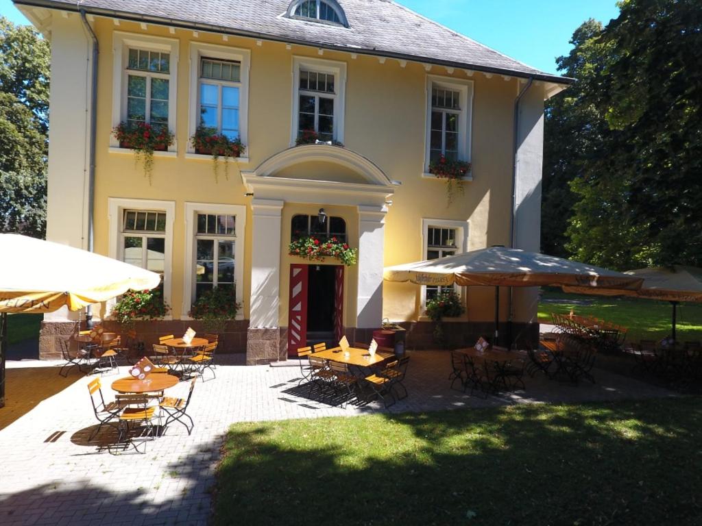 une maison avec des tables et des parasols devant elle dans l'établissement Hotel Villa Wirtshaus Köpenick, à Hofgeismar