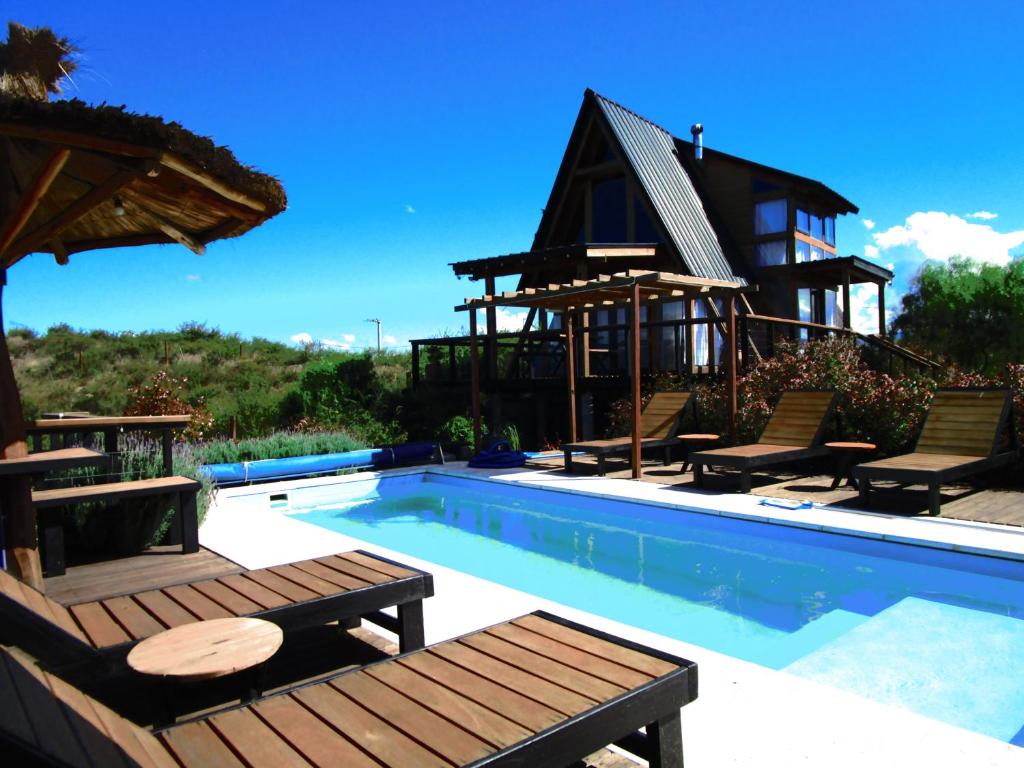 a swimming pool with a house in the background at Torii Cabañas de Montaña in Villa Carlos Paz
