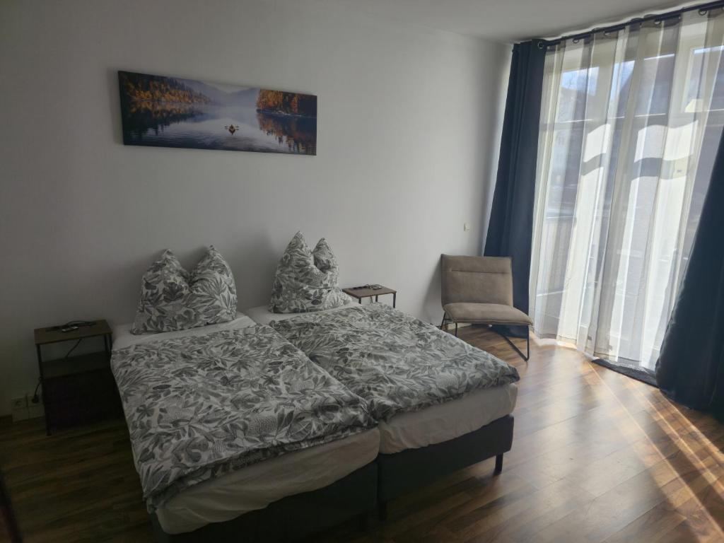 a bedroom with a bed and a chair and windows at TechisFerienWohnung in Magdeburg