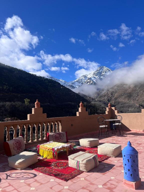 a patio with a table and chairs and a mountain at Atlas Green Lodge in Imlil