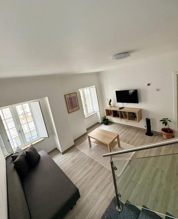 a living room with a couch and a tv at Oeste Garden Suites in Caldas da Rainha