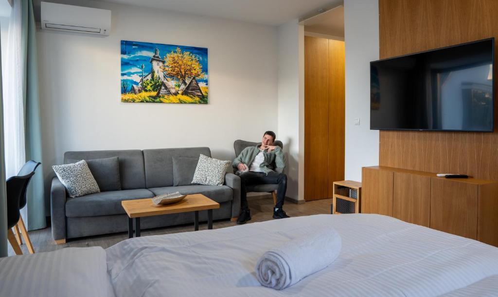 a man sitting in a chair in a hotel room at Liptov Hills in Liptovský Mikuláš