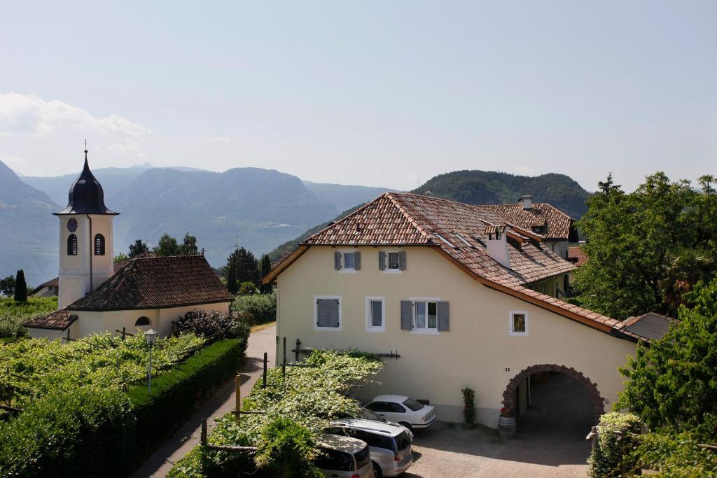 a building with a church and cars parked in a driveway at Fischerhof Agriturismo in Cornaiano