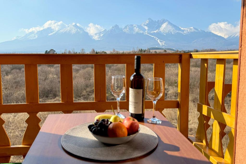 a table with a bowl of fruit and a bottle of wine at Apartmán Mountain View - Tatragolf C in Veľká Lomnica