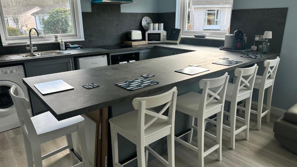 a kitchen with a large island with white bar stools at 3 bedroom cottage in Lamlash