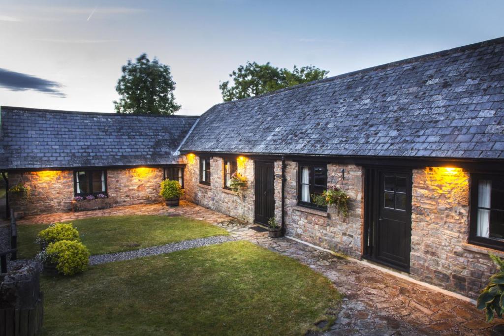 an exterior view of a stone house with a yard at The Long Barn nr Huntsham in Tiverton