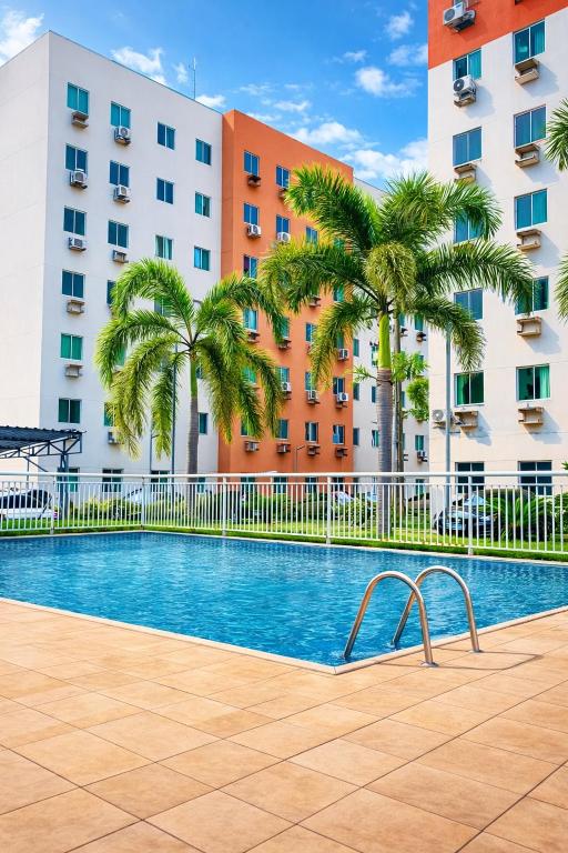 a swimming pool in front of a building with palm trees at Apto1 - Próximo ao Shopping Metrópole in Ananindeua