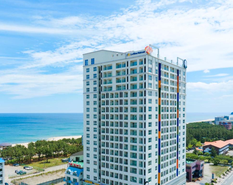 a tall white building with the ocean in the background at Chestertons Naksan in Yangyang