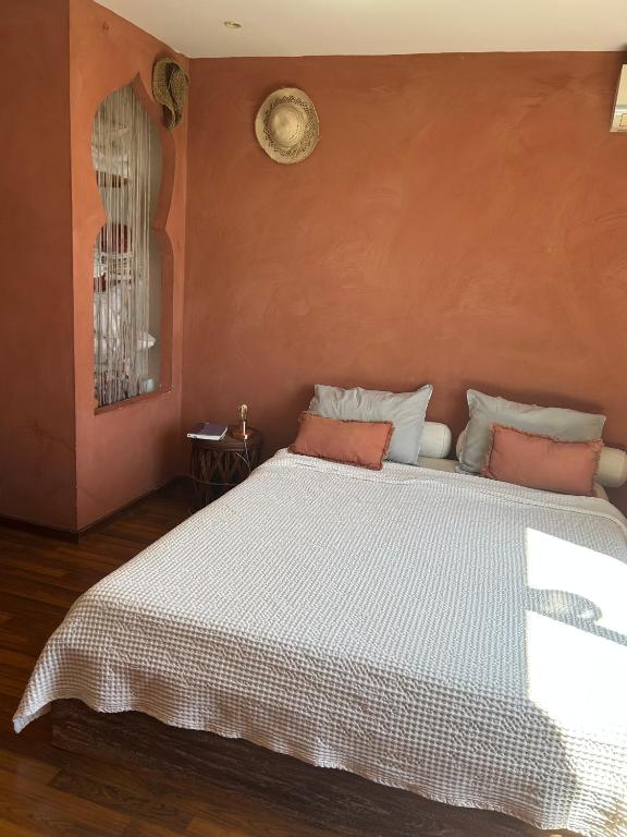 a bedroom with a large white bed with orange walls at Villa Annaga in Saint-Paul