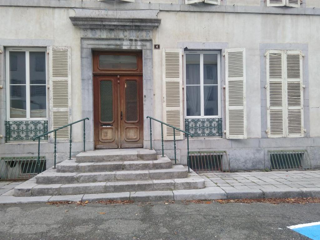 a building with a wooden door and stairs in front at Appartement Eaux bonnes in Eaux-Bonnes