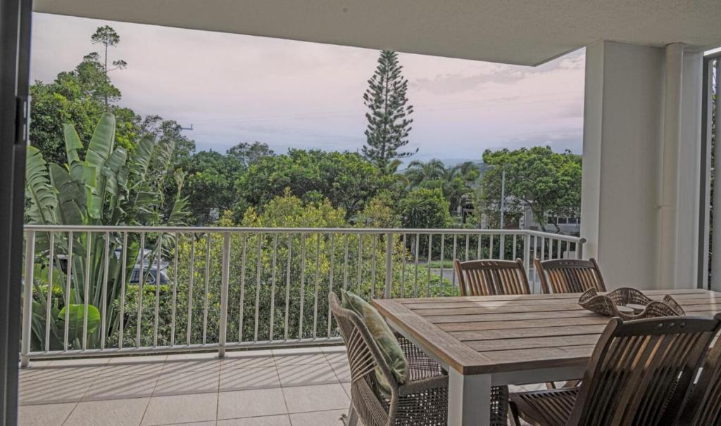 a patio with a wooden table and chairs on a balcony at Drift North Beachfront Apartments - Private Apartments in Kingscliff