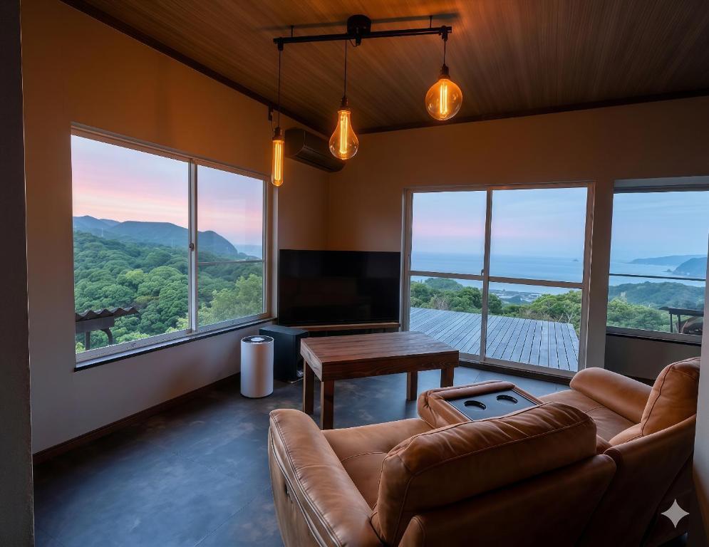 a living room with a couch and a table and windows at Maison N in Shimoda